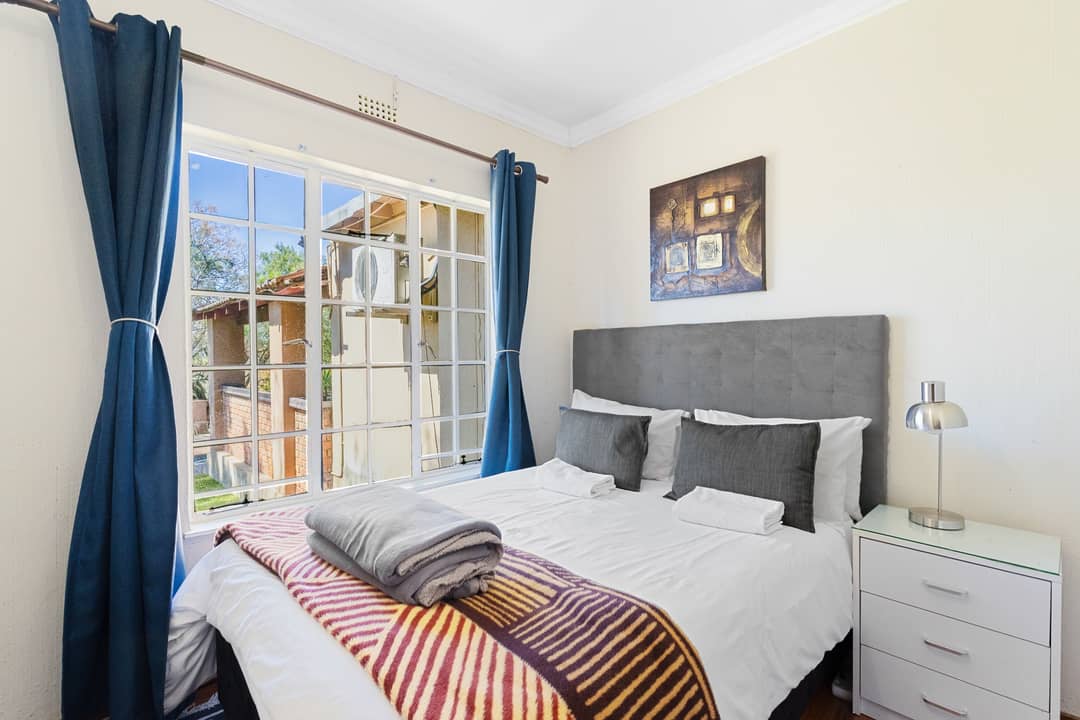 Bedroom with blue curtains and a garden view