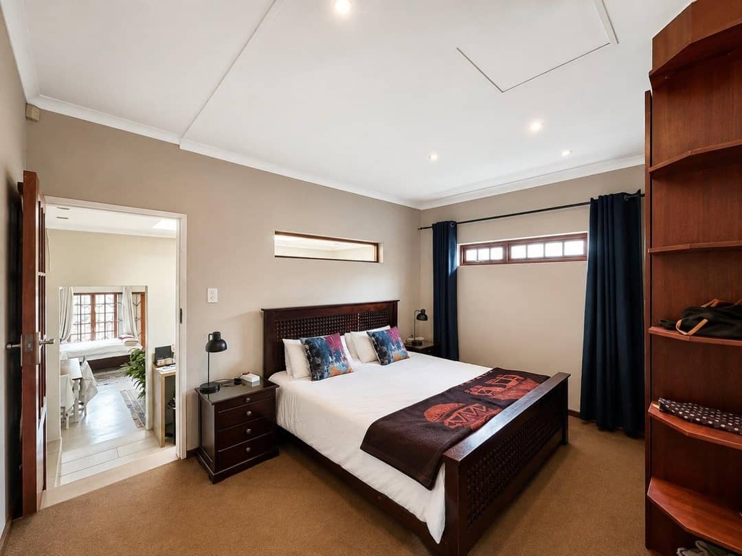 Downstairs bedroom with a dark wooden sleigh bed, navy curtains and a clerestory window