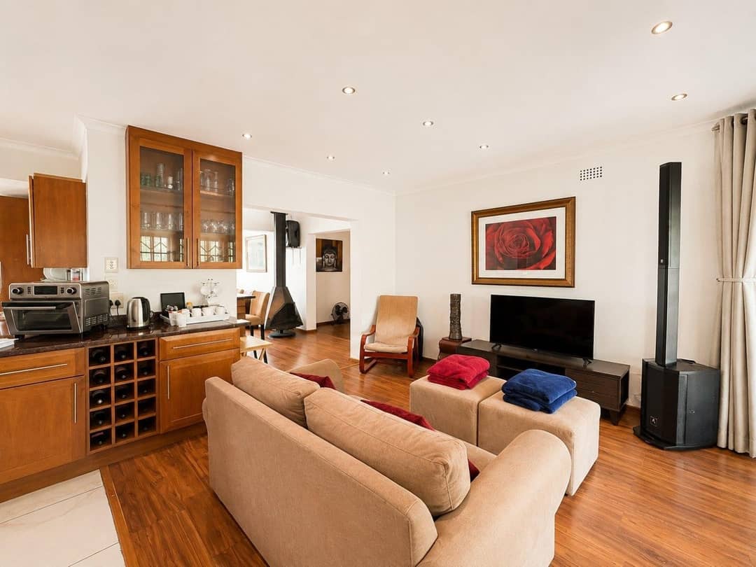 TV lounge with cream sofas, a wood-burning stove and a kitchenette with wine rack along one wall