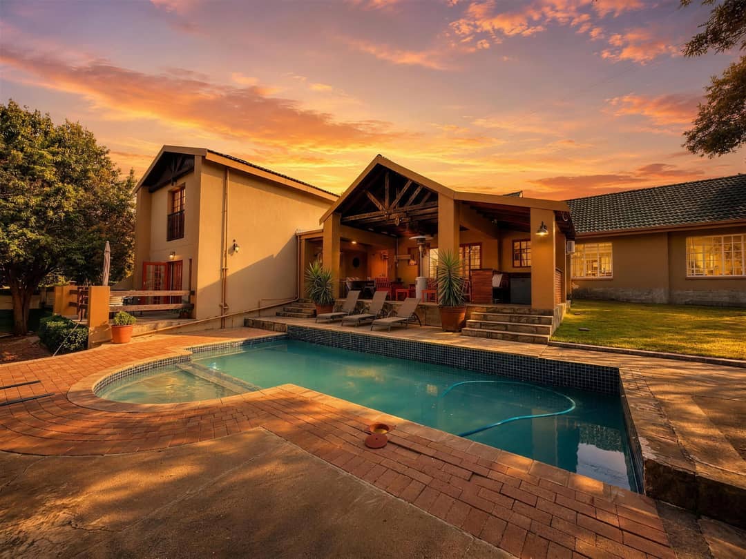 The house at sunset, with the swimming pool and covered patio lit under an orange sky