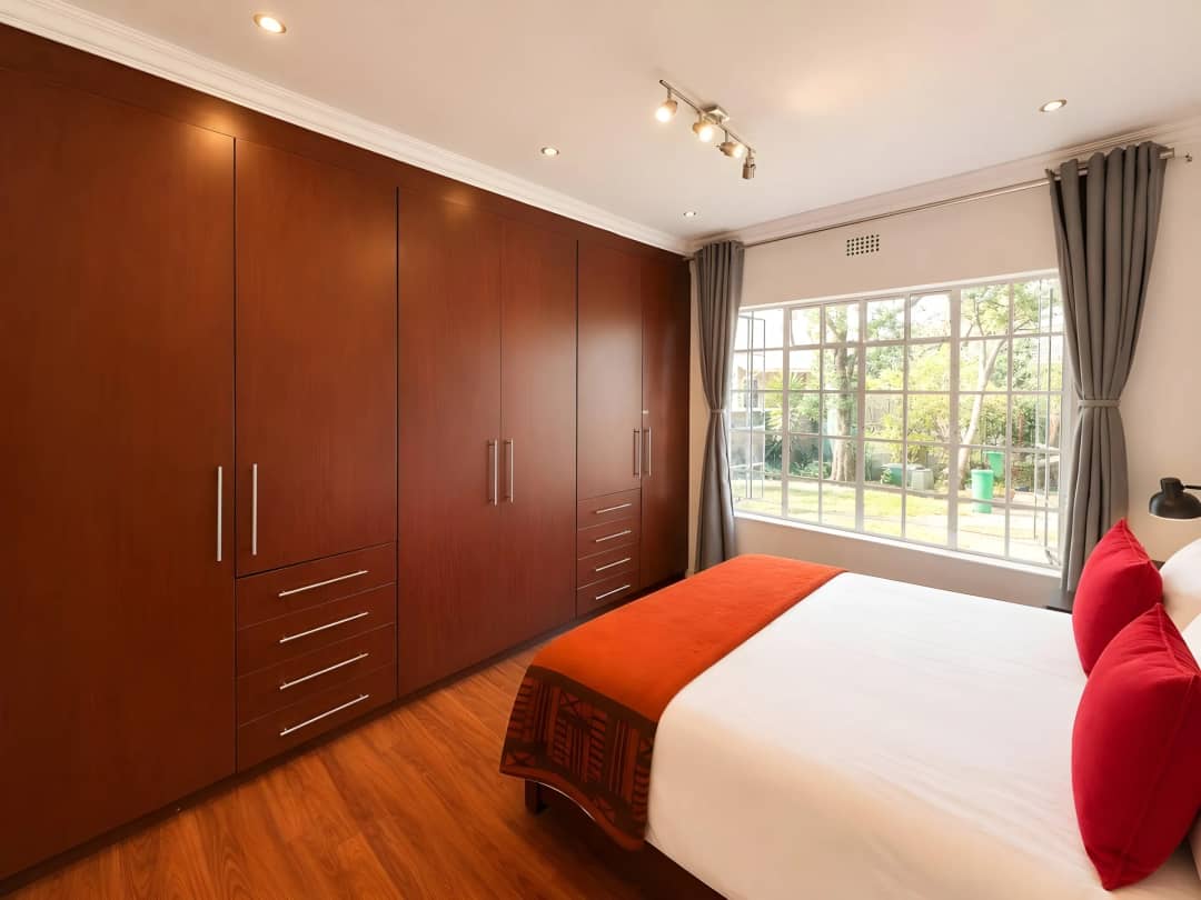 Main bedroom with a full wall of mahogany built-in cupboards and a garden-facing window